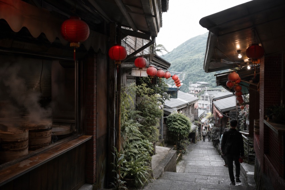 Red lanterns hanging over a narrow sloped lane of old shopfronts in Jiufen Old Street