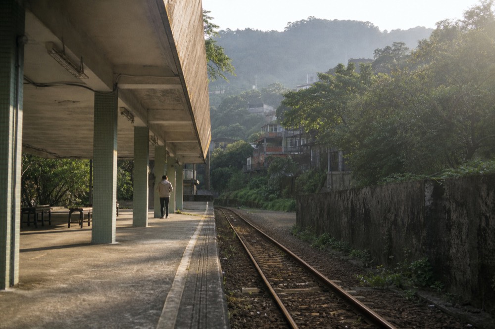 A single-track rural railway line running between steep wooded hills above a river