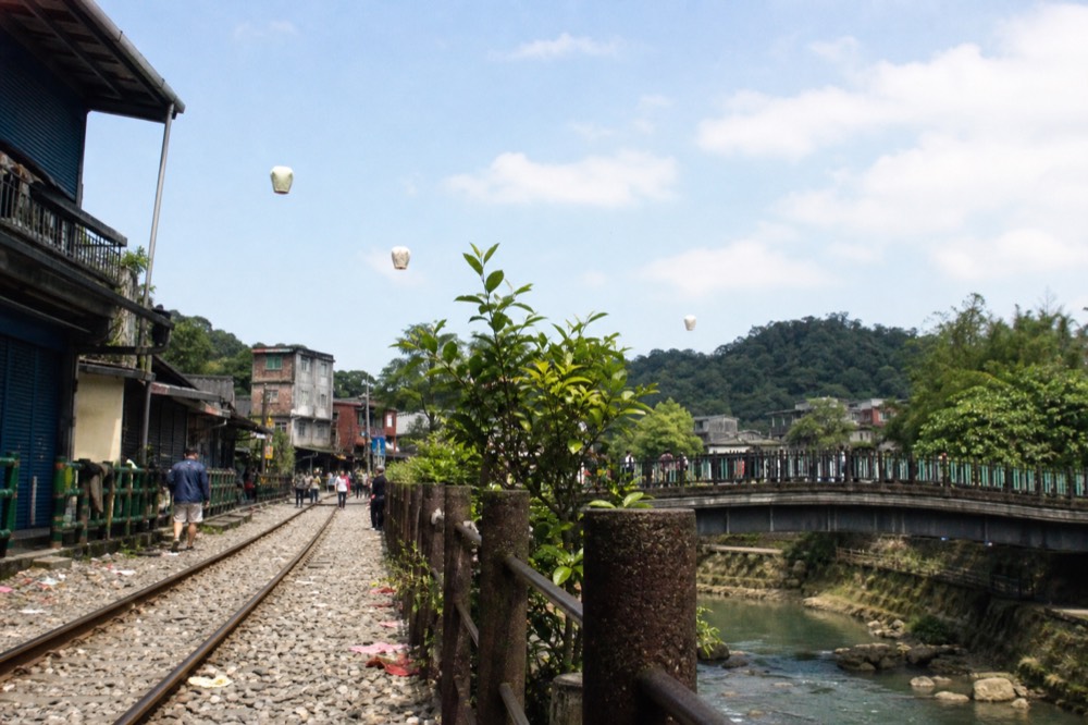 Sky lanterns rising above a railway bridge over a river gorge in a small mountain town