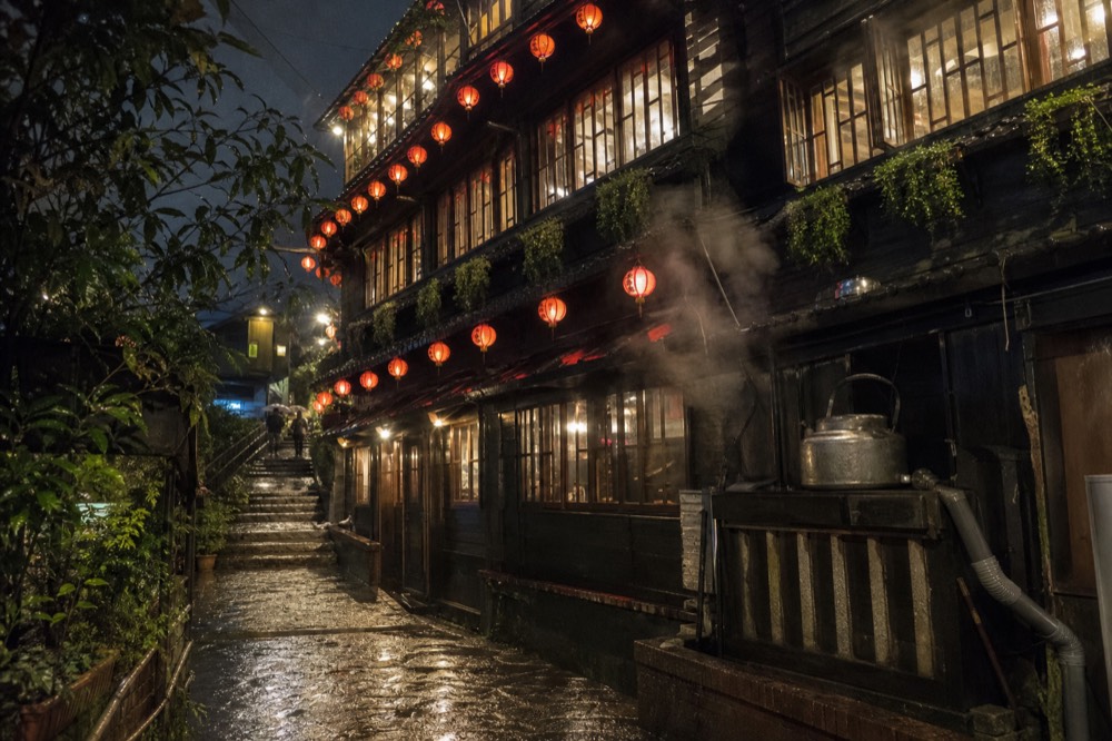 Lanterns lighting a steep stone stairway between old tea houses after dark