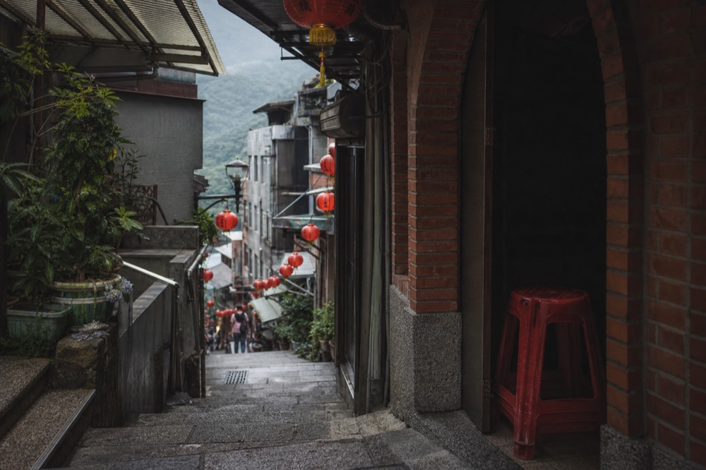 A steep narrow lane of old brick buildings climbing a hillside under lantern light