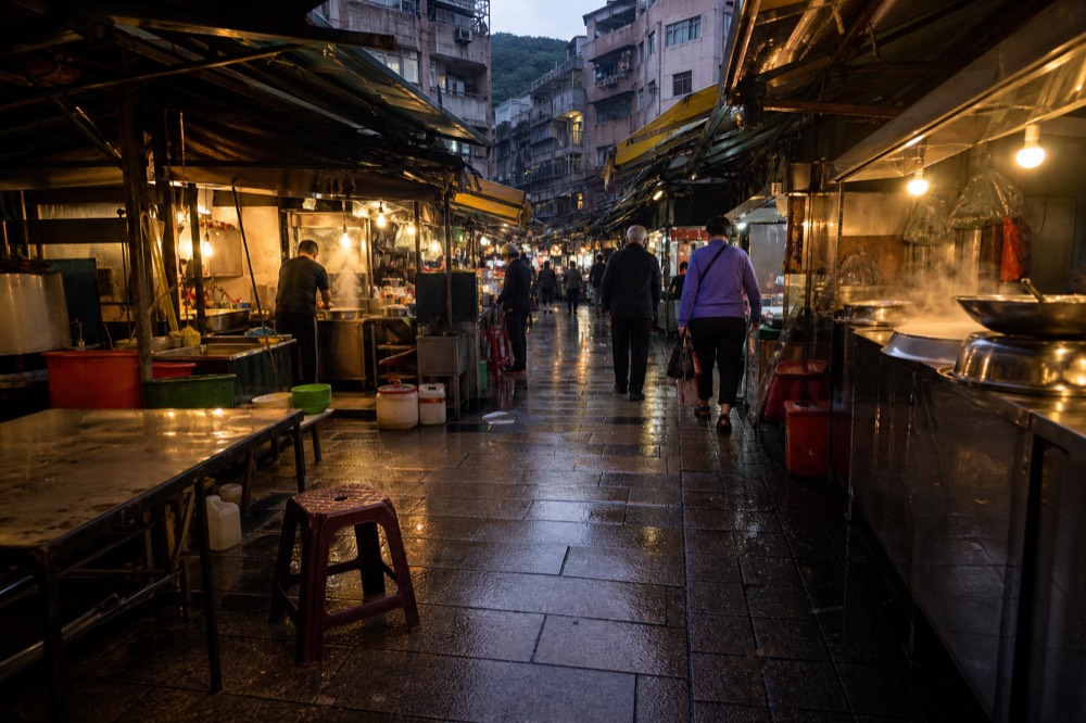 Narrow food street with hanging shop signs and awnings along both sides