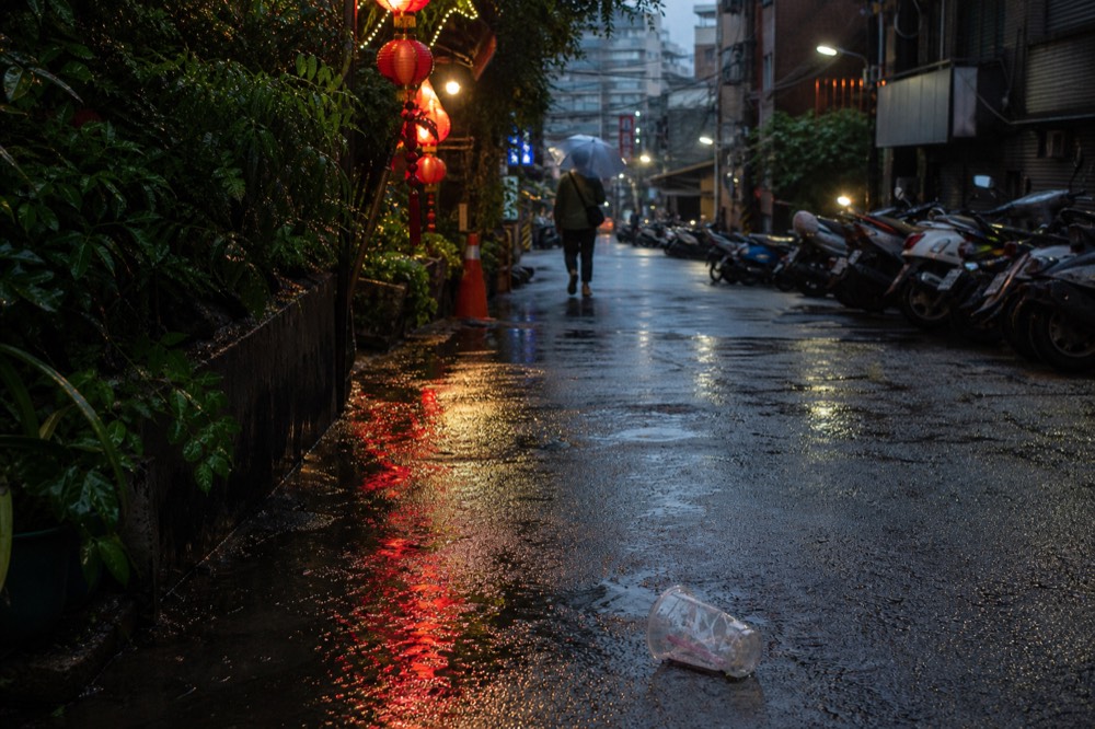 Rain-slicked street with reflections of shop lights on wet pavement