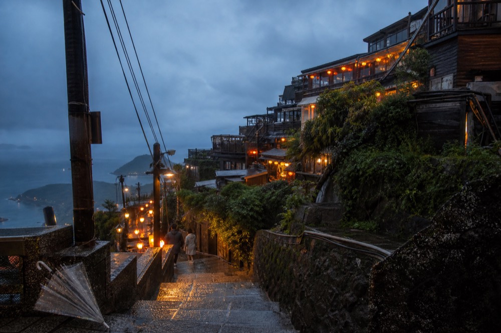 Hillside town lights glowing under low cloud at dusk seen from the harbour approach