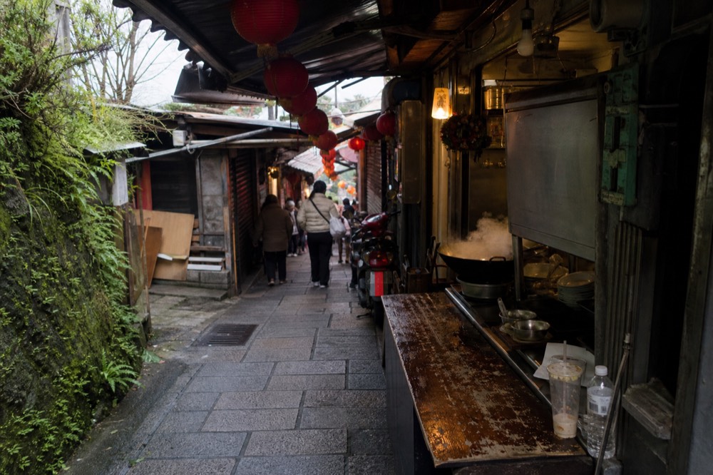 Narrow old street lane in Jiufen lined with food stalls and red lanterns