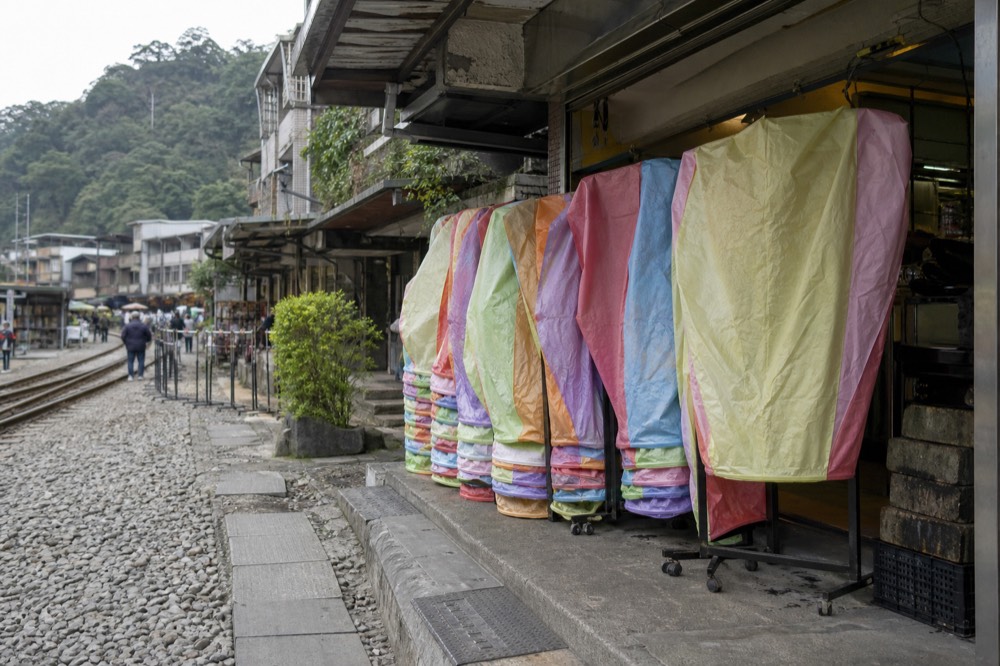 Rows of colourful paper sky lanterns stacked beside a shopfront on a narrow old street