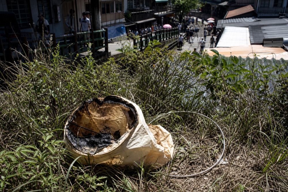 A spent paper lantern resting among grass and low scrub on a hillside