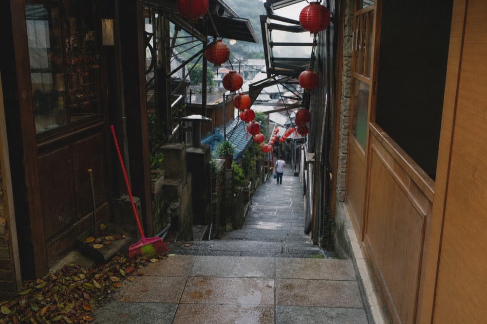 Red lanterns hung in rows along a covered shopping lane in daylight
