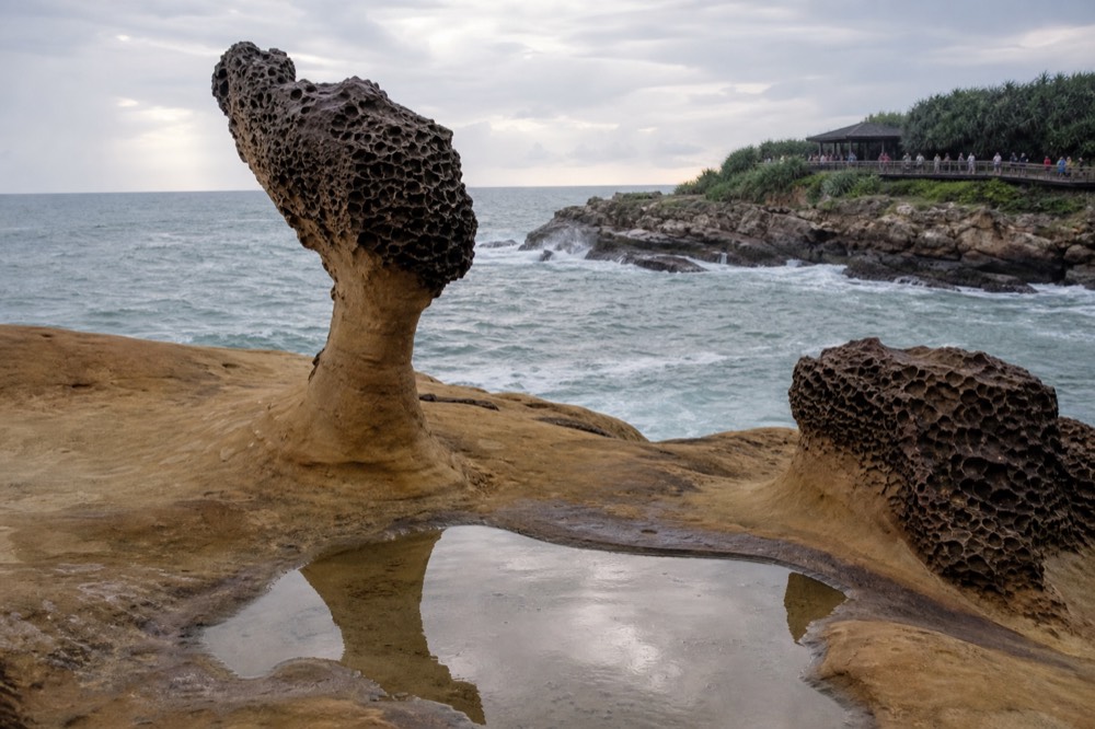 A coastal headland with weathered rock formations under a partly cloudy sky