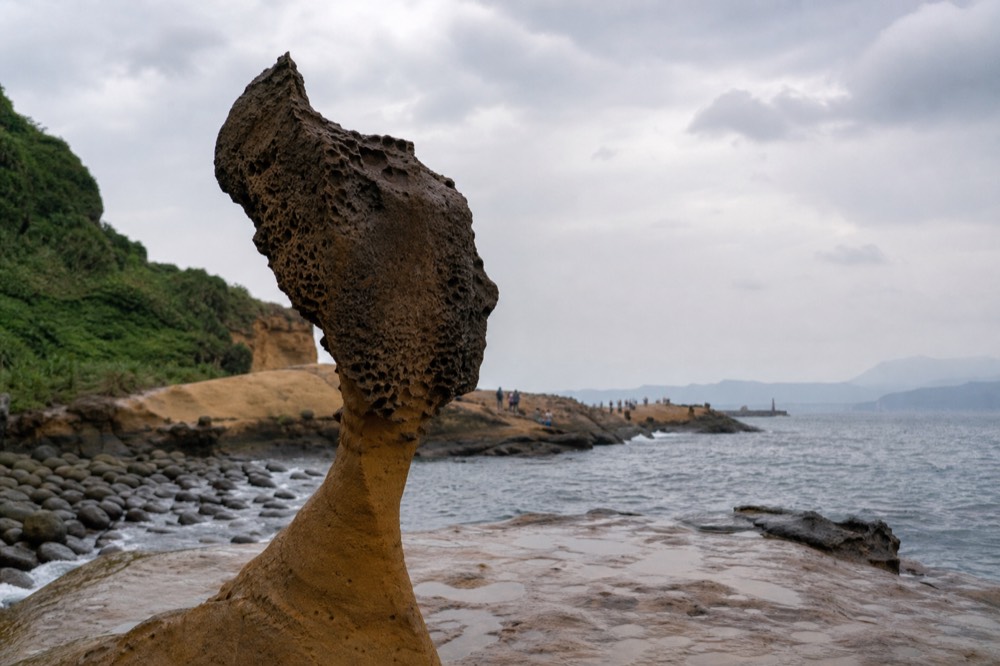 Coastal rock formations on a headland beside a grey sea under an overcast sky