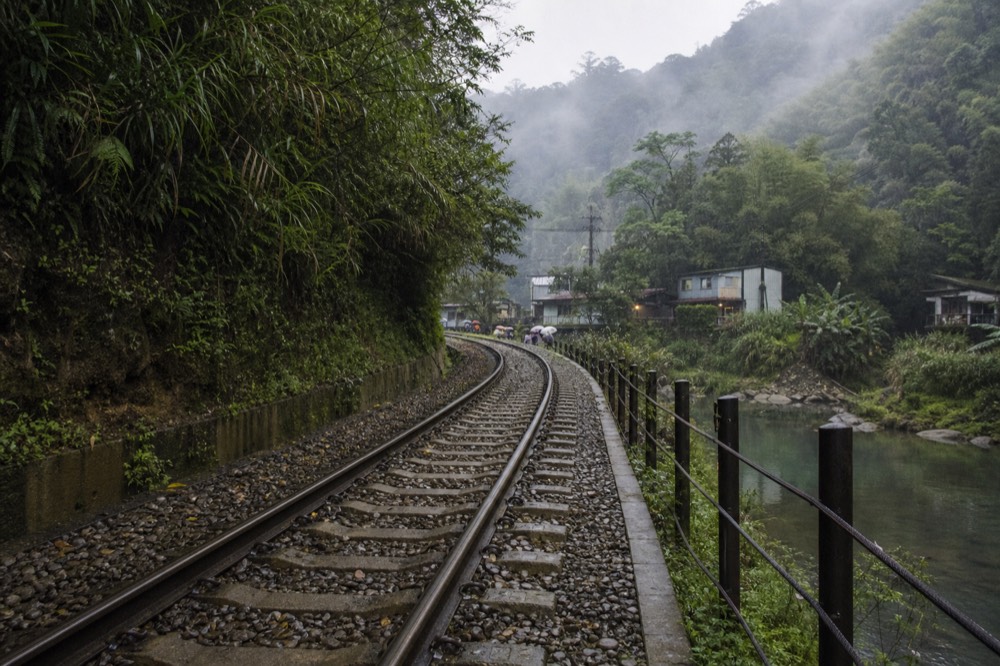 Morning mist settling over a river valley with a railway line running beside the water and hills above