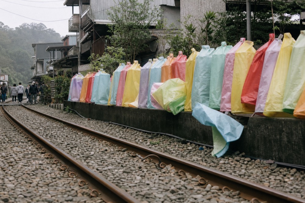 Rows of coloured paper sky lanterns stacked beside a railway track