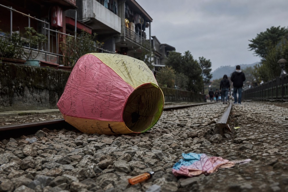 A paper lantern being lit at ground level beside a railway line