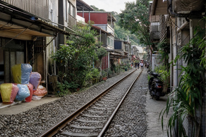 A railway track running through a small town street in northern Taiwan, with lanterns and shopfronts along the line