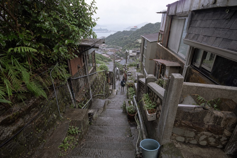 Steep lanes of a hillside town with tiled roofs descending toward a grey sea