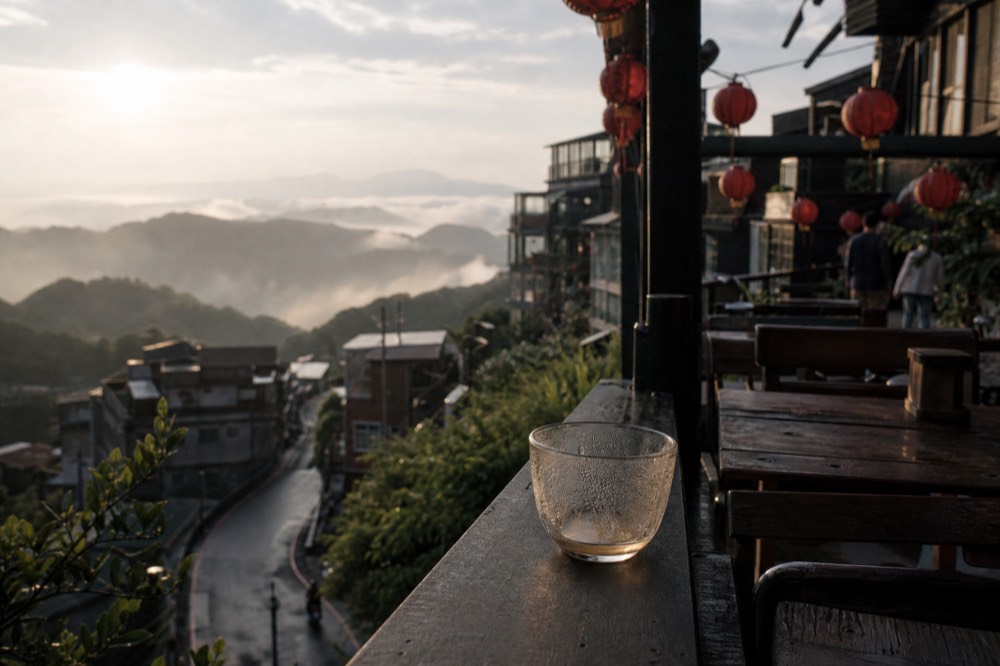 Teahouse balconies and red lanterns above a valley filled with morning mist