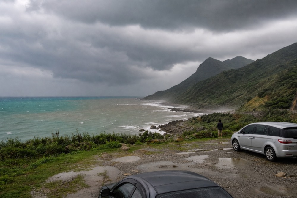 Dark storm clouds over a coastal headland with a rocky shoreline below