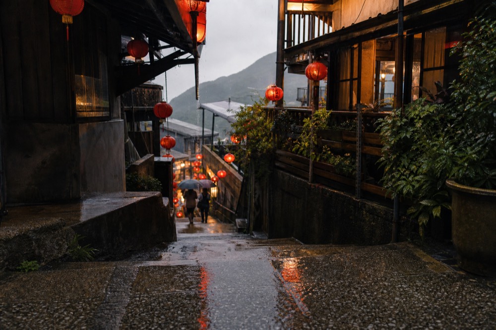 A stone stepped alley between tea houses with red lanterns overhead