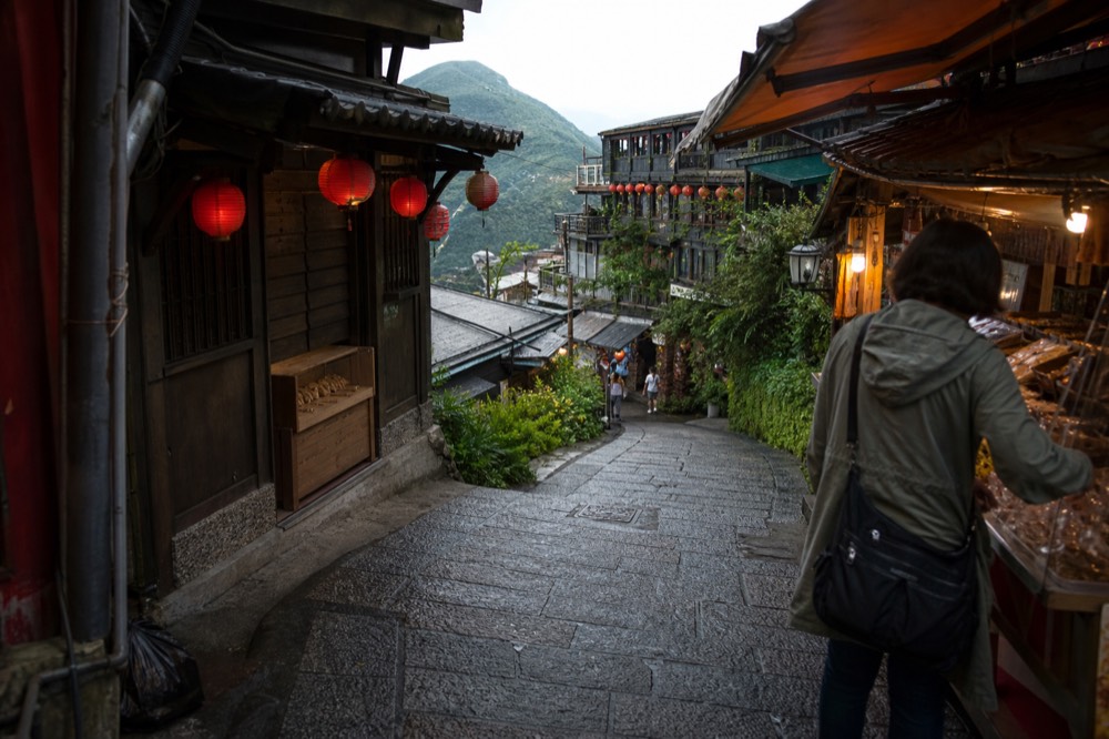 Lanterns and shopfronts along a curved stone street on a hillside