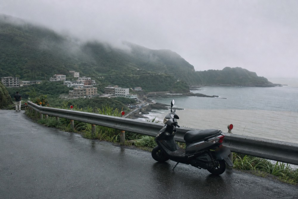 Fog drifting over a hillside town above a grey sea