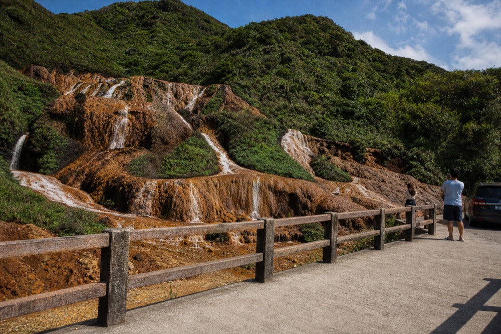 A small waterfall of rust-orange water cascading over iron-stained rock