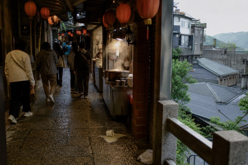 A busy Jiufen Old Street on a weekend afternoon, with visitors crowding the narrow lane under red lanterns