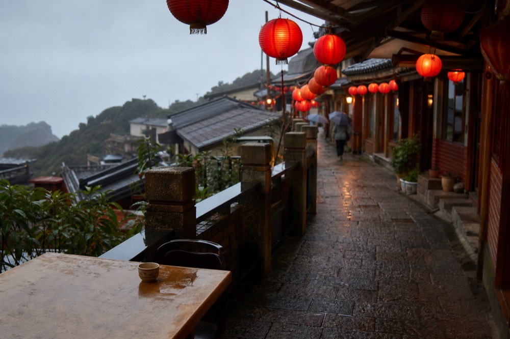 Red paper lanterns strung overhead along an old street as daylight fades