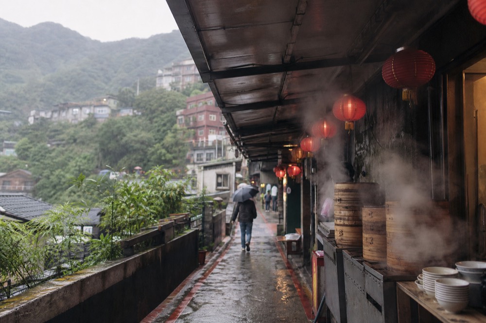 Food stall fronts and hanging red lanterns inside a covered market lane on a hillside