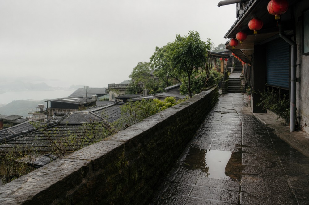 A quiet flat stone lane between low walls and old buildings on a hillside