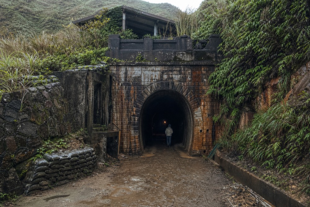 An old stone mine tunnel portal set into a green hillside