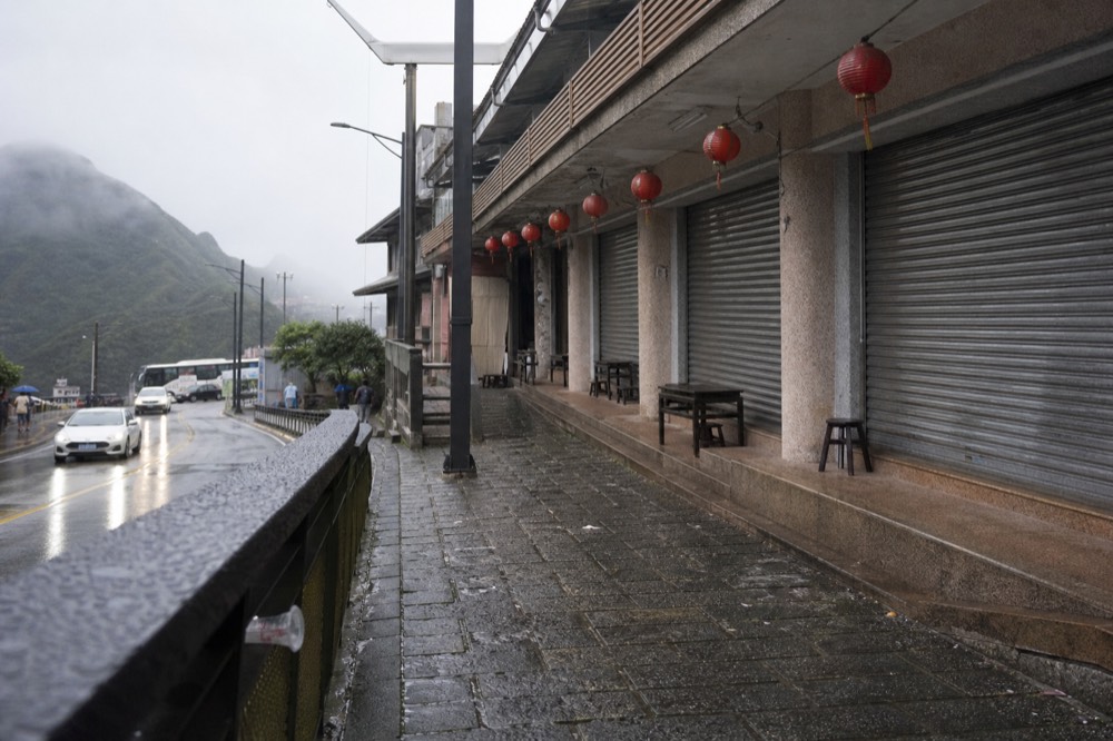 An empty old street with shuttered shopfronts and hanging lanterns in early morning light