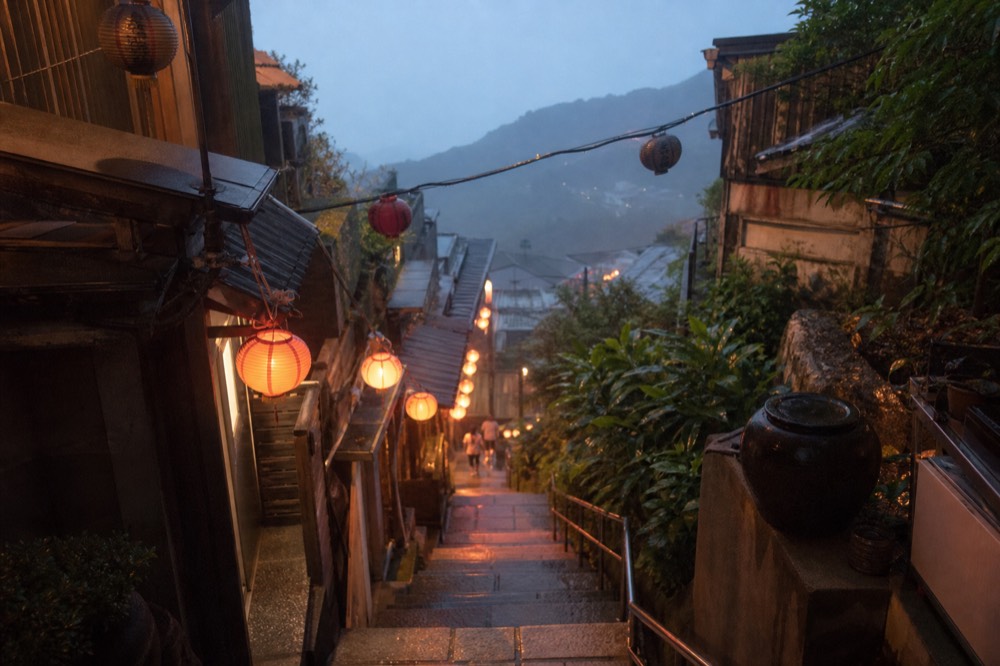 Red lanterns glowing along a stone stairway in the evening