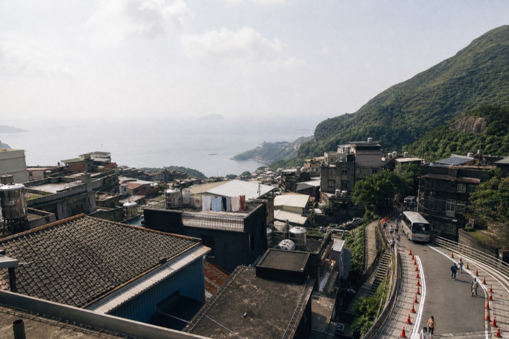 Mountain town rooftops descending toward the sea in afternoon light