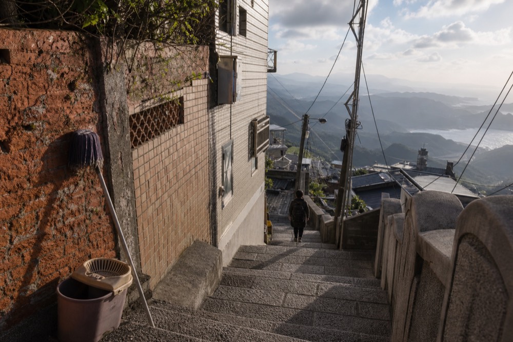 Steep stairway between old buildings with mountain and sea beyond