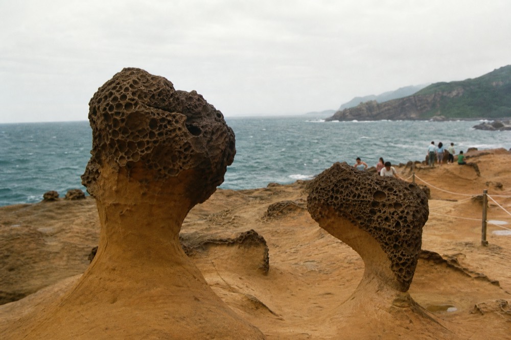 Weathered rock formations on a coastal cape under a cloudy sky