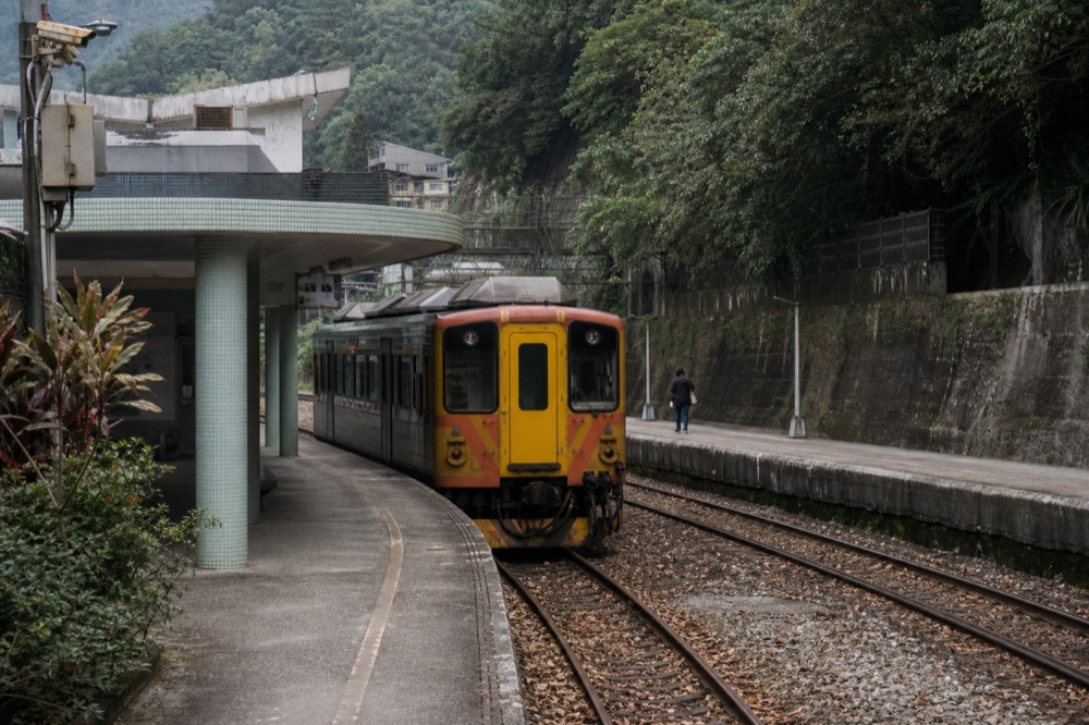 A single-car branch line train waiting at a small rural station platform