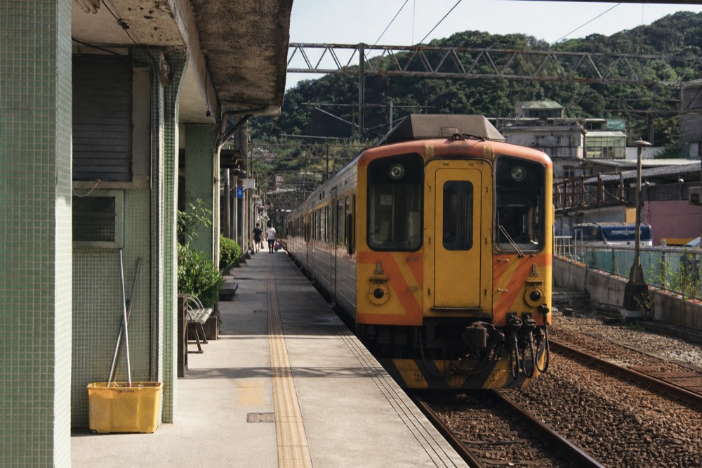 A small single-carriage diesel train waiting at a rural station platform