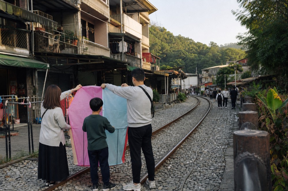 A group of people holding a large paper lantern ready to release beside a railway track