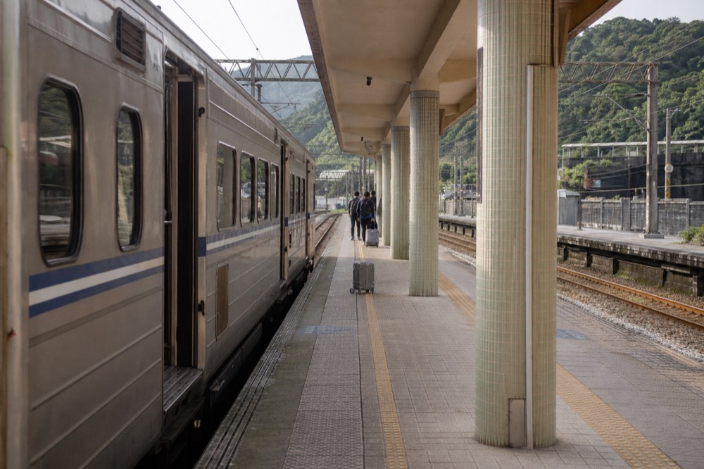 A railway platform in Taiwan with a train stopped beside waiting passengers