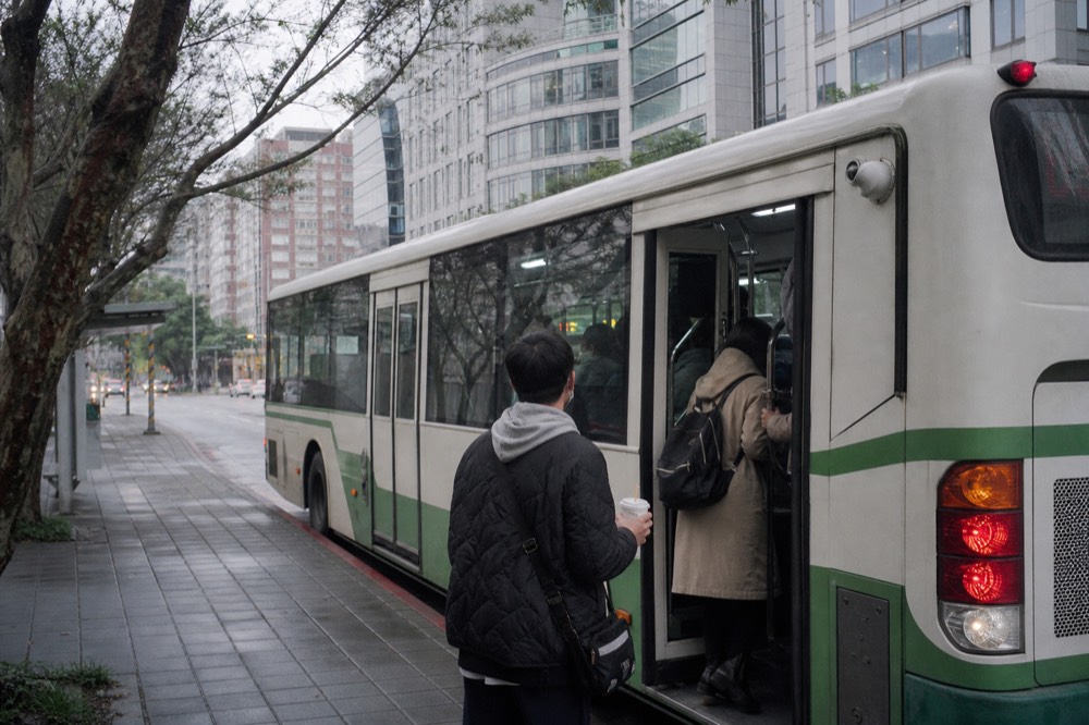 A city bus stopped at a curb on a street in Taipei