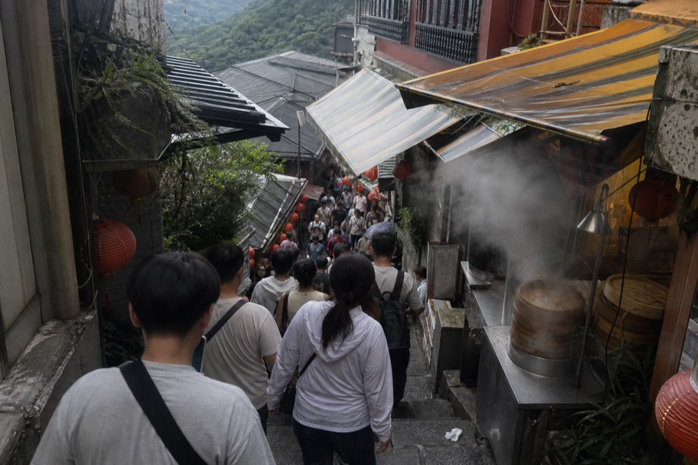 A crowded narrow street of shops and visitors on a hillside old street