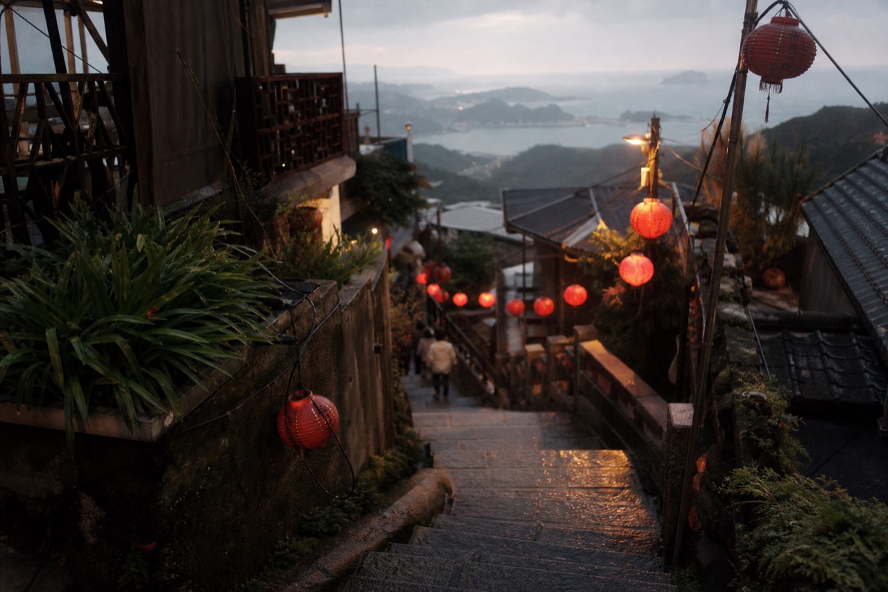 A narrow lane of lantern-lit teahouses stacked on a hillside above the sea in Jiufen