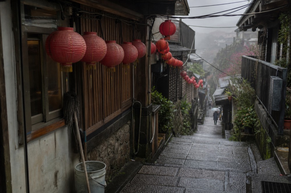Red lanterns hanging over a narrow stone-paved shopping street on a Taiwanese hillside