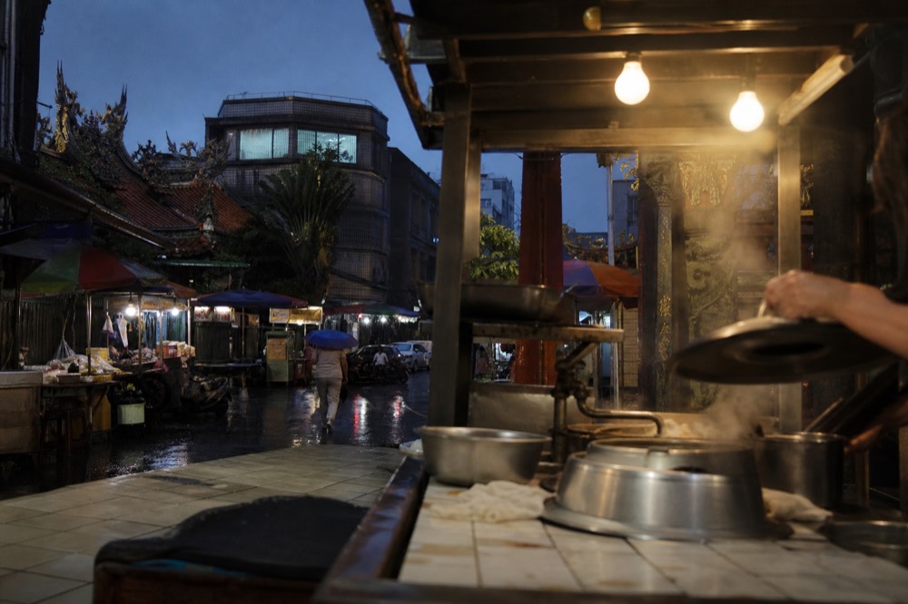 A night market stall in Keelung with steaming pots of seafood and bright signs