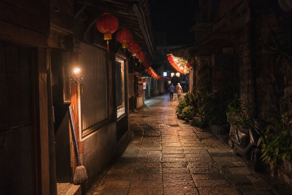 Lantern-lit stone lane in Jiufen at night with tea house signs glowing