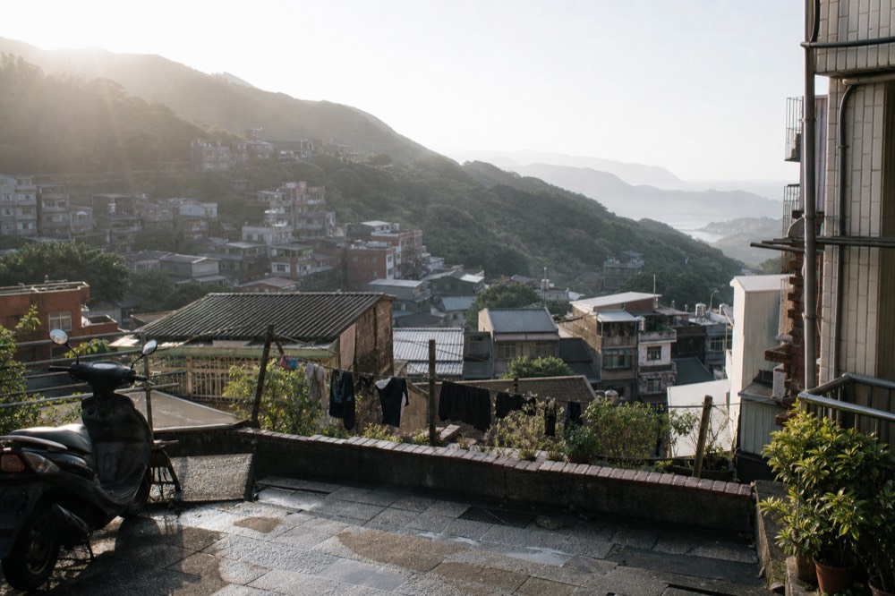Hillside rooftops of a mountain town descending toward the sea in morning light