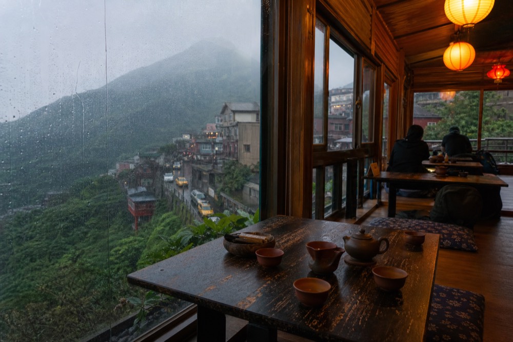 A wooden tea house interior with low tables and paper lanterns in the evening
