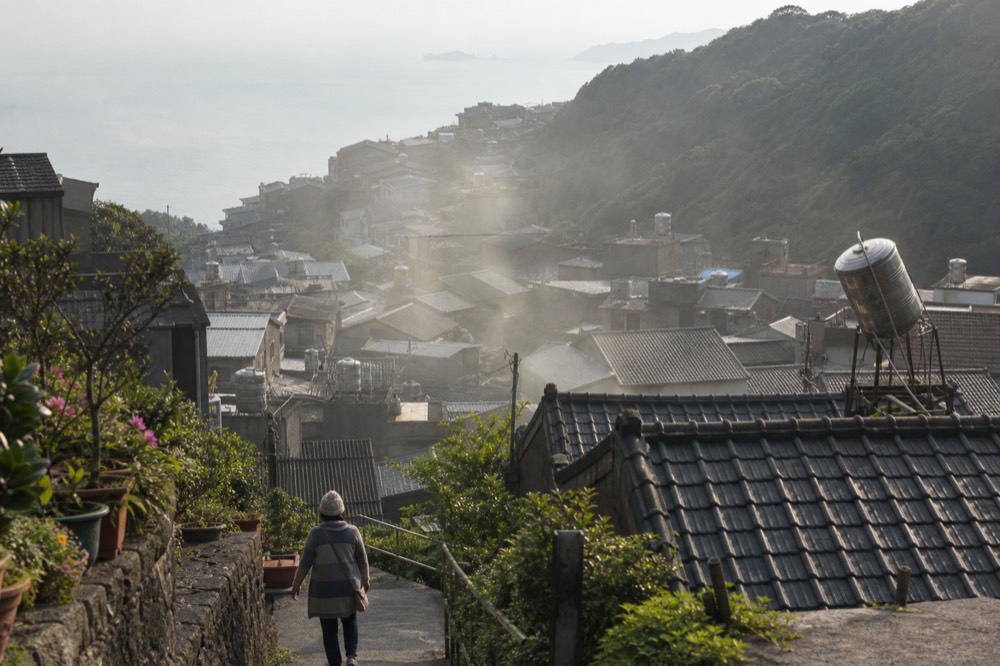 Morning mist drifting over hillside rooftops above the sea