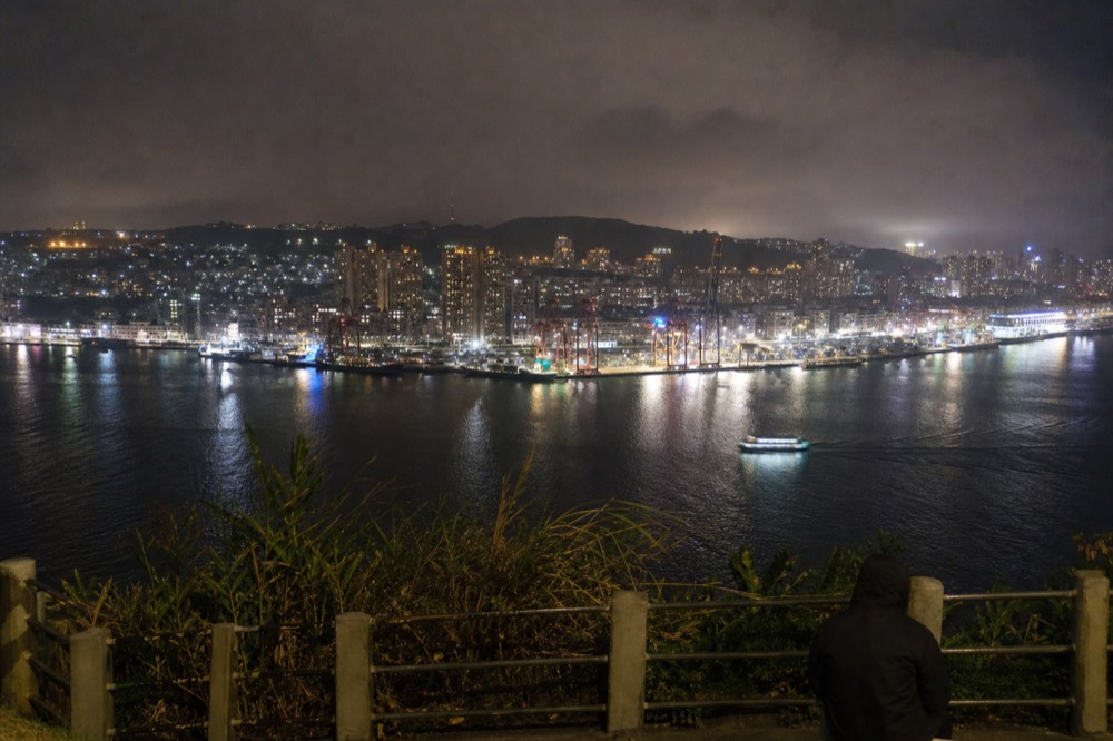 A coastal city skyline at night with a lit waterfront promenade