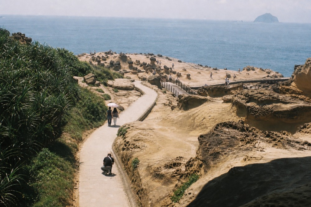 Visitor walkway winding between eroded rock formations at a coastal geopark